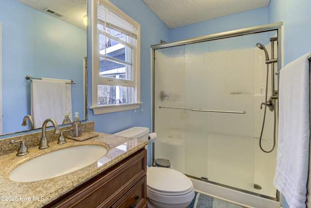 full bathroom featuring visible vents, toilet, a stall shower, a textured ceiling, and vanity