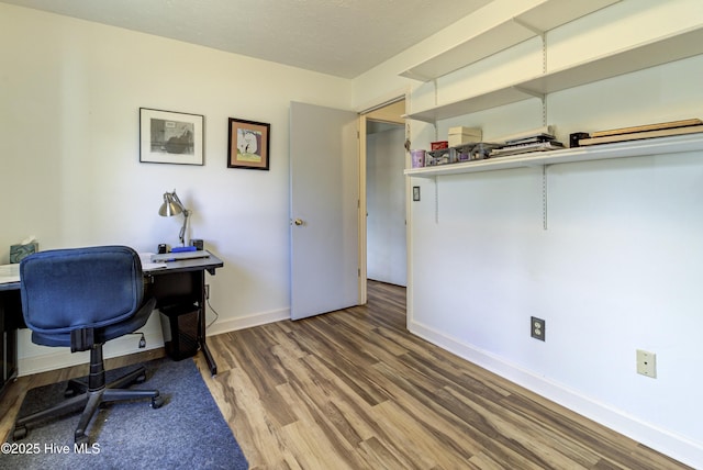 home office featuring a textured ceiling, baseboards, and wood finished floors