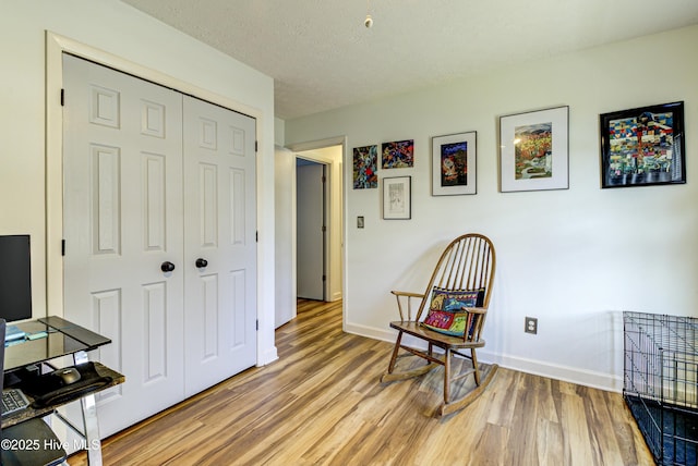 sitting room with baseboards, a textured ceiling, and light wood finished floors