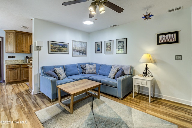 living room with visible vents, light wood-type flooring, and baseboards