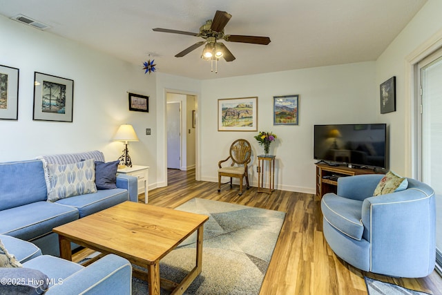 living area featuring baseboards, wood finished floors, visible vents, and ceiling fan