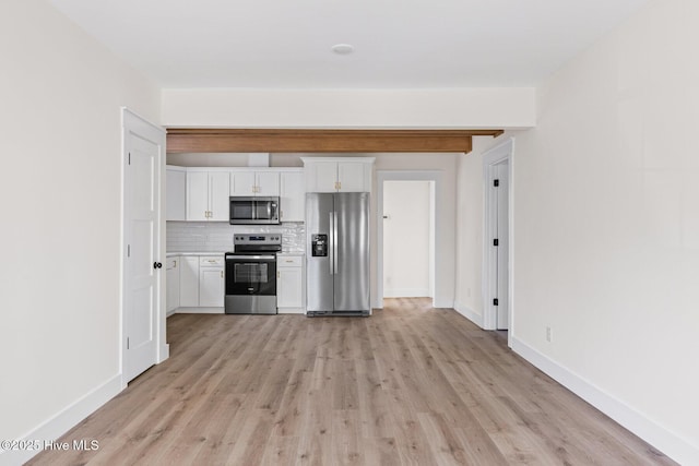 kitchen with light wood finished floors, baseboards, white cabinets, appliances with stainless steel finishes, and backsplash