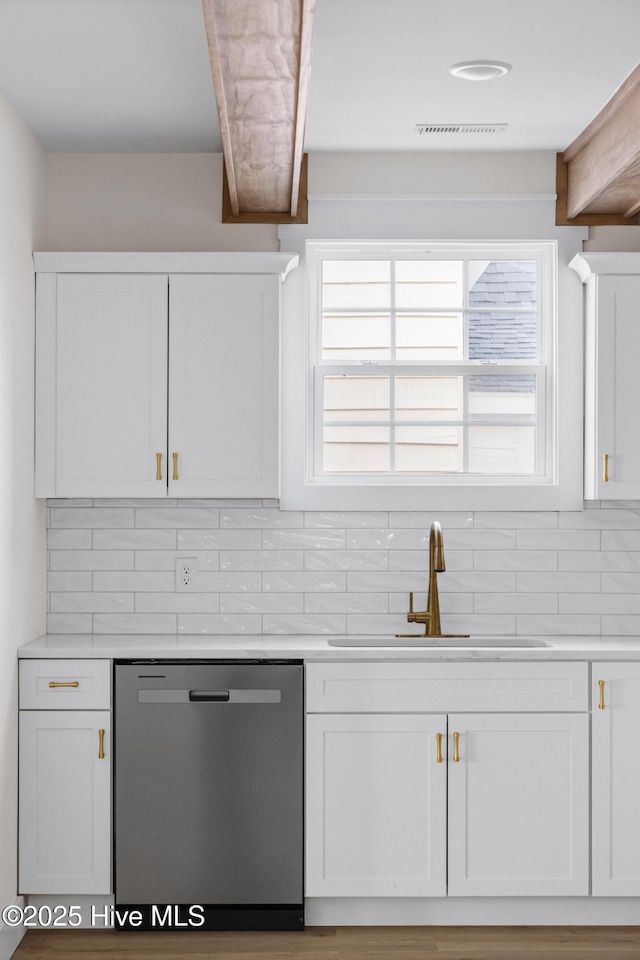 kitchen featuring a sink, white cabinetry, light countertops, dishwasher, and tasteful backsplash
