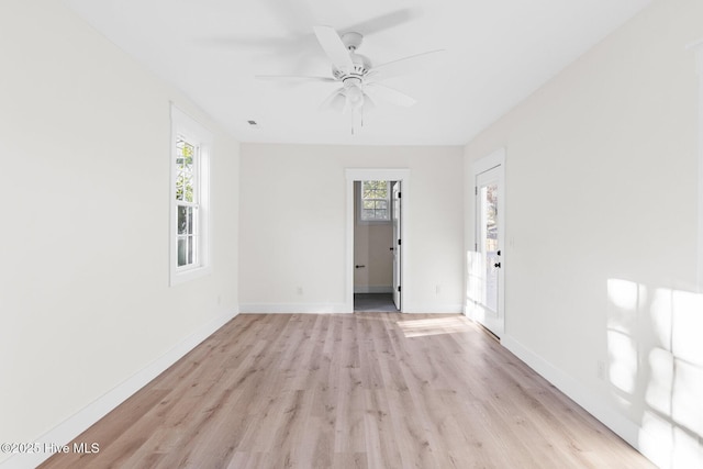 unfurnished room featuring light wood-type flooring, a wealth of natural light, and baseboards