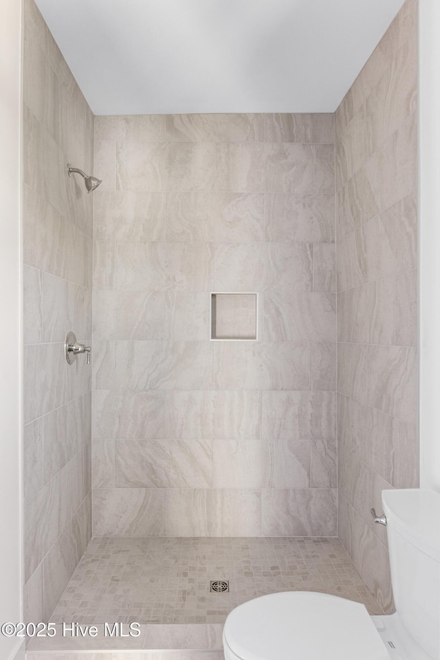 bathroom featuring a tile shower and toilet