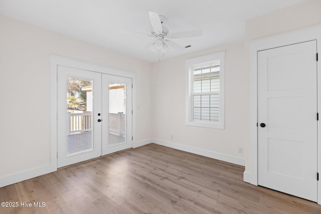 spare room featuring french doors, a healthy amount of sunlight, baseboards, and wood finished floors
