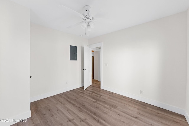 spare room featuring wood finished floors, electric panel, and baseboards