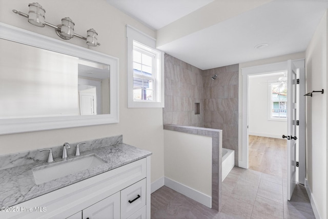 full bath featuring vanity, a wealth of natural light, and baseboards