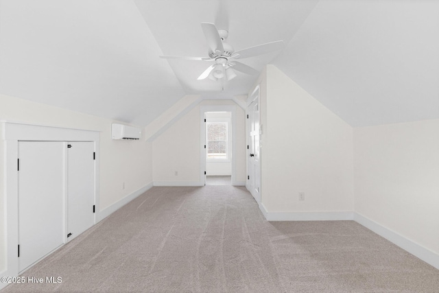 additional living space featuring lofted ceiling, light colored carpet, an AC wall unit, ceiling fan, and baseboards
