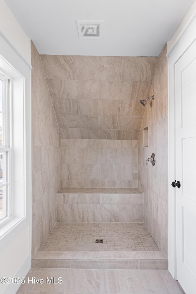 bathroom with visible vents and tiled shower