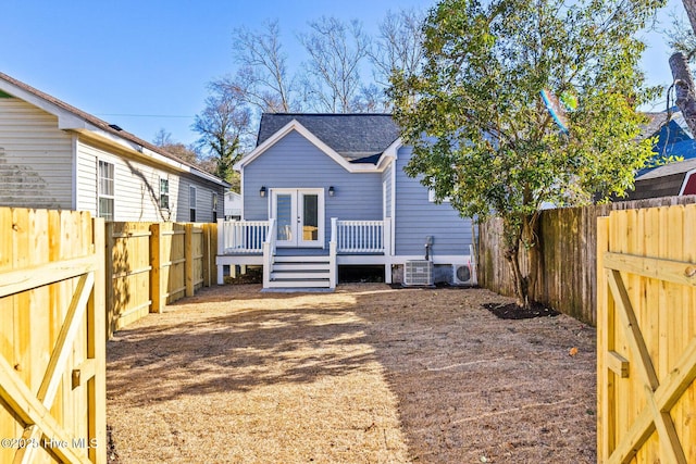 back of house with central air condition unit, a wooden deck, a fenced backyard, and french doors