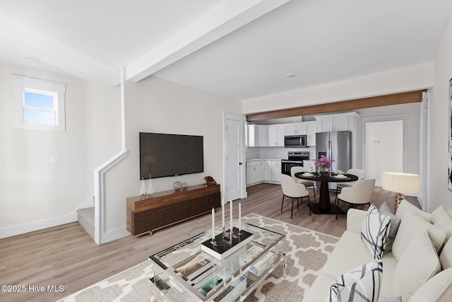 living area with light wood finished floors, stairs, baseboards, and beam ceiling