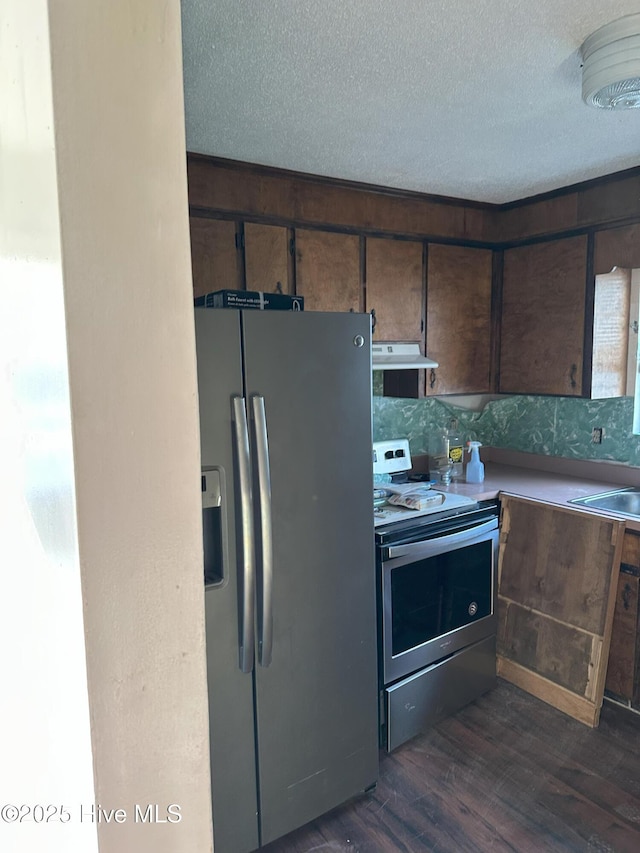 kitchen featuring under cabinet range hood, a textured ceiling, stainless steel appliances, and dark wood-style flooring