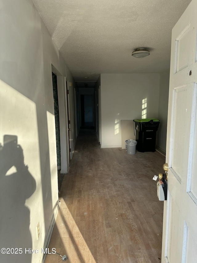 corridor with a textured ceiling and wood finished floors