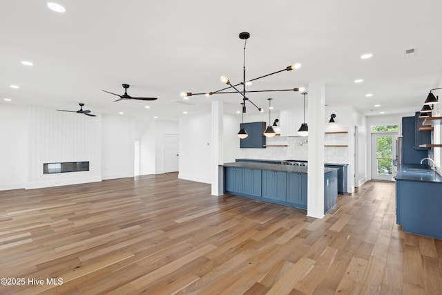 kitchen featuring dark countertops, a large fireplace, pendant lighting, and open floor plan