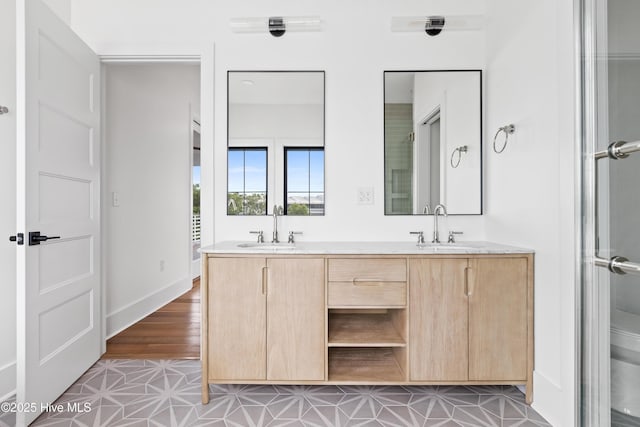 bathroom featuring double vanity, baseboards, and a sink