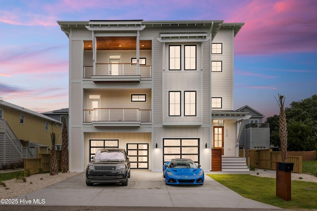 view of front facade with a balcony, driveway, an attached garage, and board and batten siding