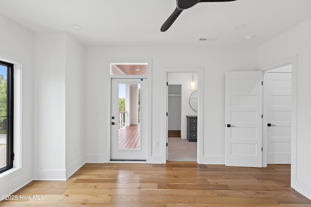 interior space featuring ceiling fan, a spacious closet, light wood finished floors, and baseboards