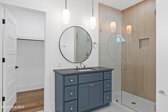 bathroom with wood finished floors, a shower stall, and vanity