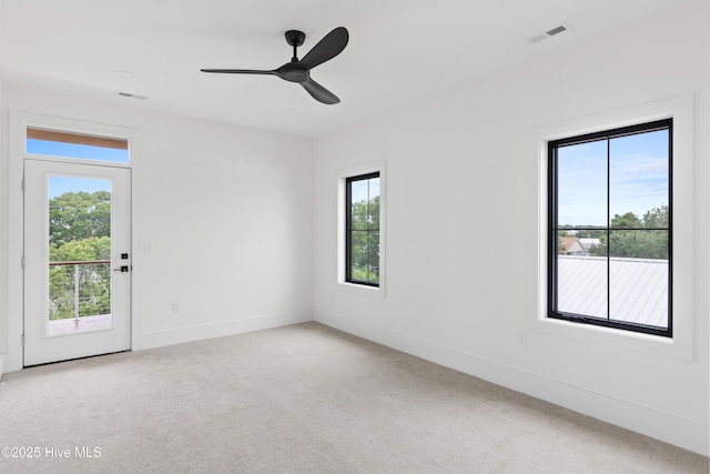 unfurnished room with a ceiling fan, visible vents, light carpet, and baseboards