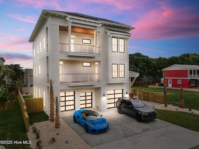 view of front facade featuring a balcony, a garage, fence, concrete driveway, and board and batten siding