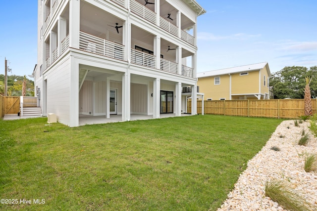 rear view of property with a patio, a lawn, a ceiling fan, board and batten siding, and a balcony