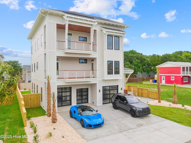 view of front of house featuring driveway, a garage, a balcony, board and batten siding, and a front yard