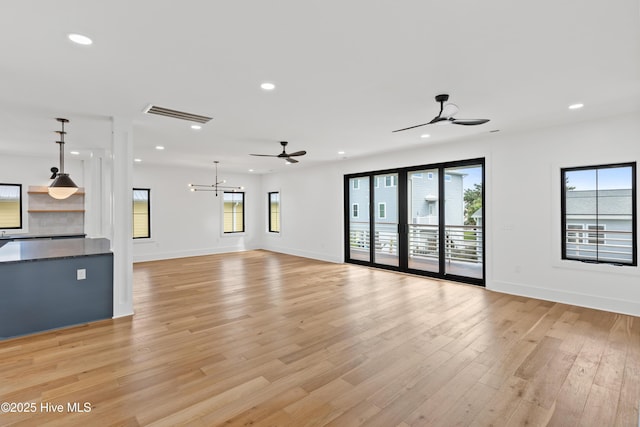 unfurnished living room with recessed lighting, visible vents, light wood-style flooring, and ceiling fan with notable chandelier