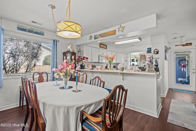 dining room featuring dark wood-style floors, baseboards, visible vents, and a textured ceiling