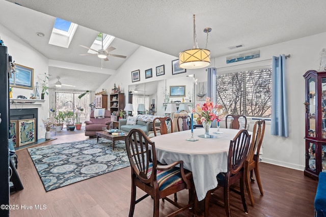 dining area featuring a textured ceiling, dark wood-type flooring, visible vents, a ceiling fan, and lofted ceiling with skylight