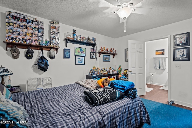 bedroom with a textured ceiling, wood finished floors, a ceiling fan, baseboards, and ensuite bath