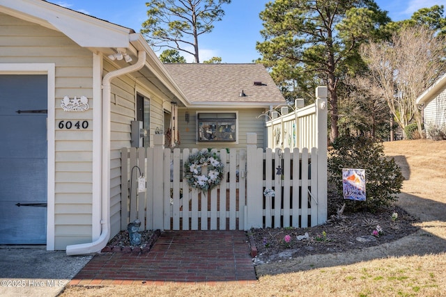 view of side of property with roof with shingles and a gate