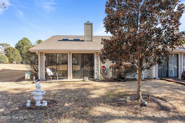 rear view of property with a shingled roof and a chimney