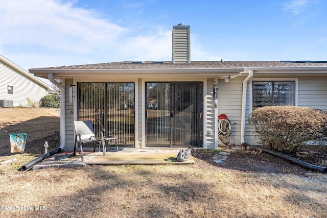 back of property with a patio area, a chimney, and roof with shingles