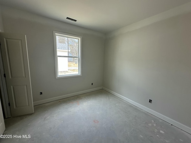 spare room featuring concrete flooring and baseboards