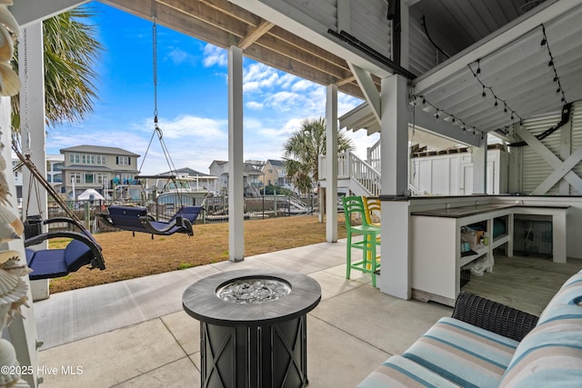 view of patio / terrace with an outdoor fire pit, exterior bar, and fence