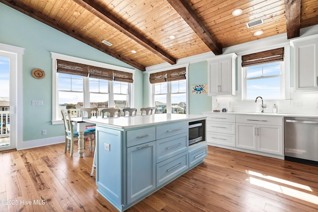 kitchen with stainless steel appliances, a kitchen island, light countertops, and white cabinets