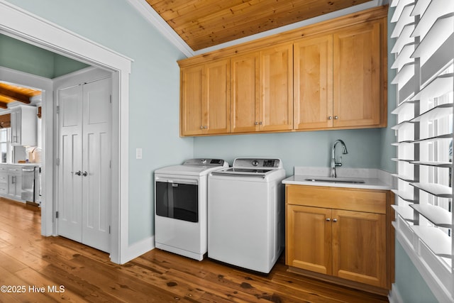 laundry area with washing machine and dryer, a sink, ornamental molding, cabinet space, and dark wood finished floors