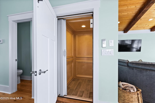 room details with a barn door, wooden ceiling, wood finished floors, and beam ceiling