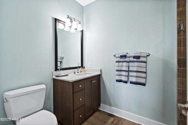 bathroom featuring toilet, baseboards, wood finished floors, and vanity