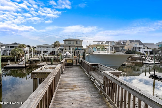 view of dock featuring a water view, boat lift, and a residential view