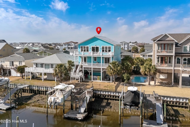 dock area with a water view, a balcony, boat lift, and a residential view