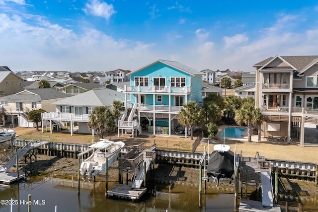 dock area featuring a residential view, a water view, boat lift, and a balcony