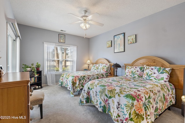 carpeted bedroom with ceiling fan, visible vents, and a textured ceiling