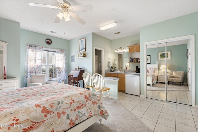 bedroom with light tile patterned floors, a textured ceiling, visible vents, and light colored carpet