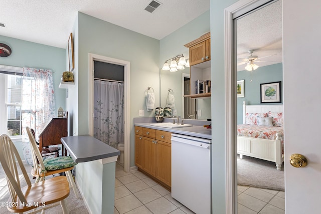 ensuite bathroom with tile patterned flooring, visible vents, a textured ceiling, and toilet