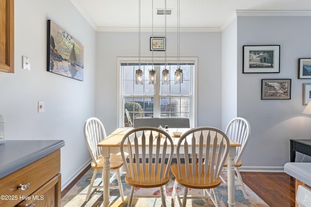 dining space with baseboards, visible vents, crown molding, and wood finished floors