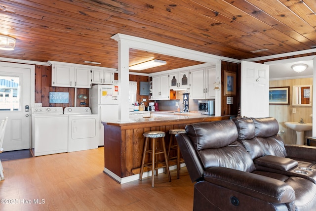 kitchen with a peninsula, separate washer and dryer, stainless steel microwave, and white cabinets