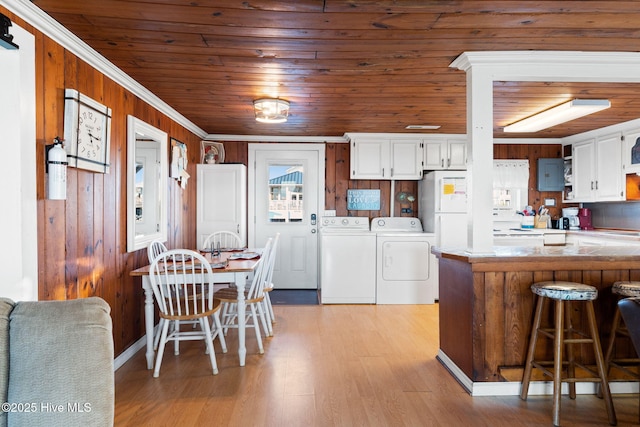 kitchen with freestanding refrigerator, a peninsula, washing machine and clothes dryer, light countertops, and white cabinetry