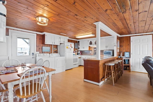 kitchen with washing machine and dryer, a peninsula, white appliances, white cabinets, and light countertops